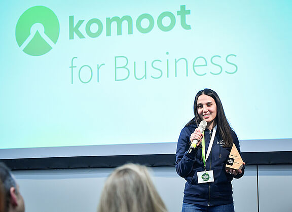 Frau redet in Mikrofon mit komoot Partner Award 2024 in der Hand