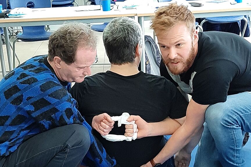 Erste Hilfe Fortbildung Erste Hilfe Fortbildung, 3 Männer bei einer Übung im Übungsraum